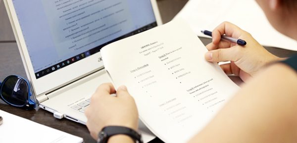 Человек с бумагой перед компьютером