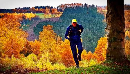 Мужчина занимается бегом в осеннем лесу