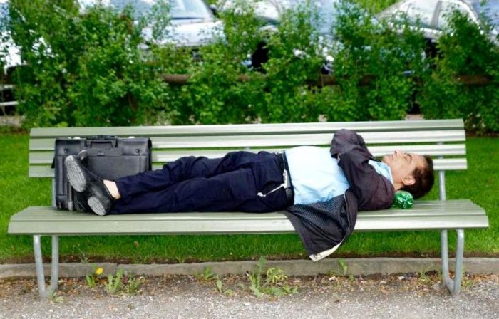 Уставший офисный мужчина спит на скамейке