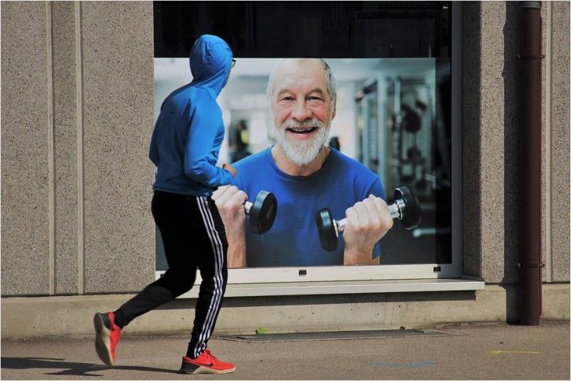 Спортсмен смотрит по телевизору тренировку.