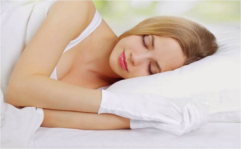 Девушка спит в специальных косметических перчатках (как ухаживать за руками зимой.