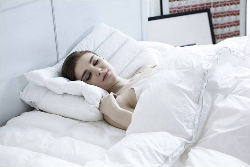 Девушка спит в белой постели, правильная температура для сна.