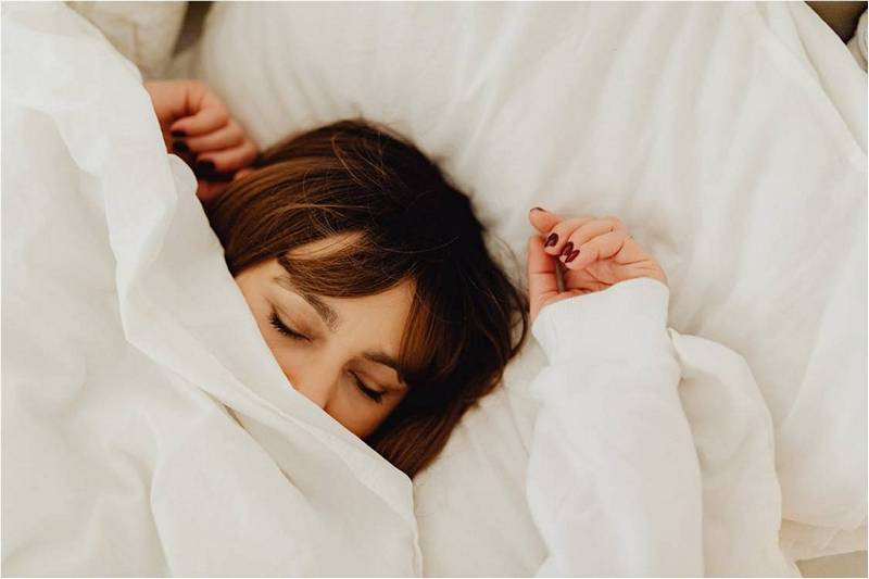 Девушка спит в белой постели, используя рецепт крепкого сна.