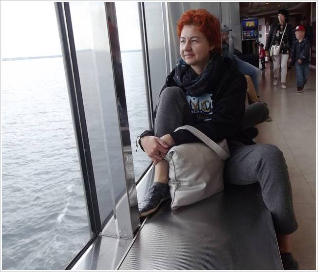 Девушка смотрит на море из окна корабля.